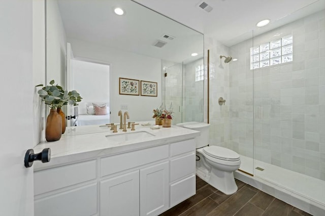 bathroom with toilet, a shower with door, and vanity