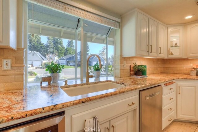 kitchen featuring white cabinets, light stone countertops, a sink, dishwasher, and beverage cooler