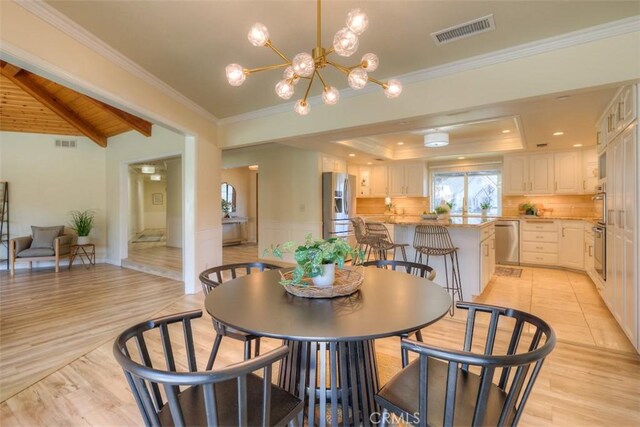 dining space featuring crown molding, a notable chandelier, visible vents, and light wood-style flooring