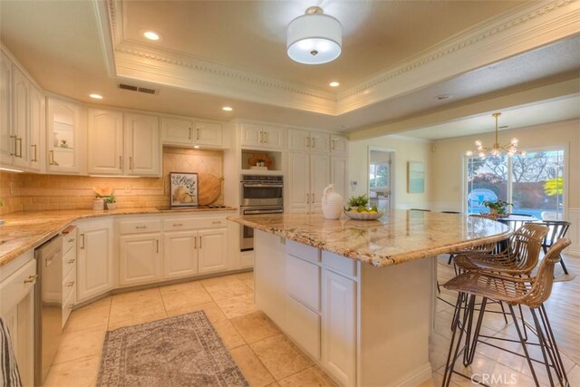 kitchen with a tray ceiling, a center island, and white cabinets