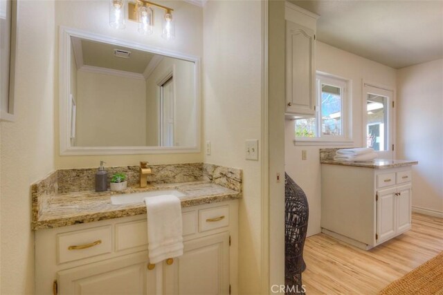 bathroom featuring vanity, hardwood / wood-style floors, and ornamental molding