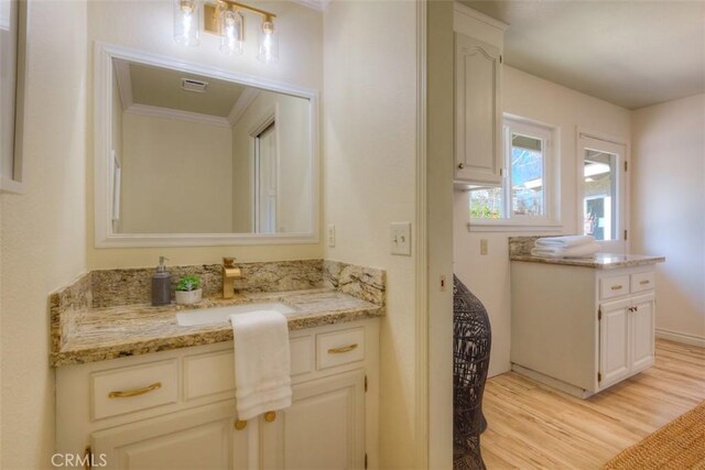 bathroom with vanity, ornamental molding, wood finished floors, and visible vents