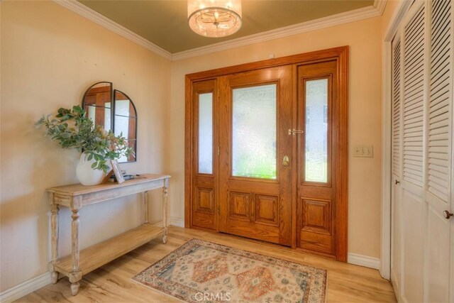 foyer featuring a notable chandelier, light hardwood / wood-style flooring, and ornamental molding