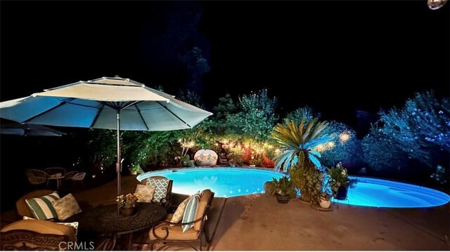 pool at twilight featuring a patio and an outdoor pool