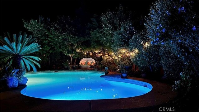 pool at night featuring an outdoor pool