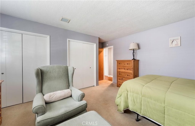 carpeted bedroom featuring multiple closets and a textured ceiling