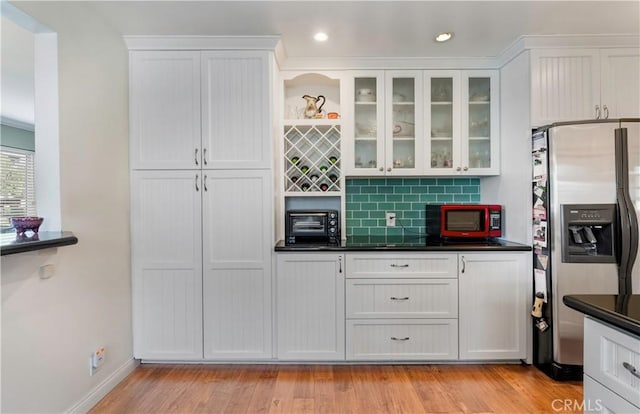 kitchen with white cabinetry, stainless steel fridge, and backsplash