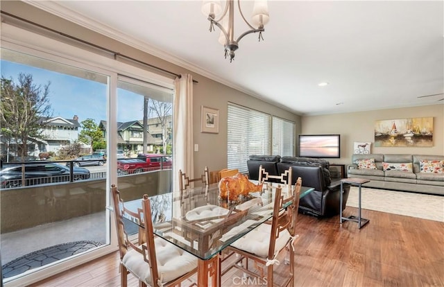 dining room with hardwood / wood-style flooring, plenty of natural light, crown molding, and a notable chandelier