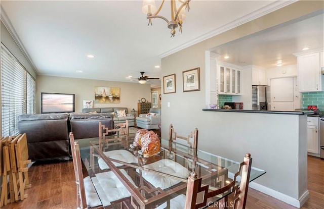 dining room with crown molding, dark hardwood / wood-style floors, and ceiling fan with notable chandelier