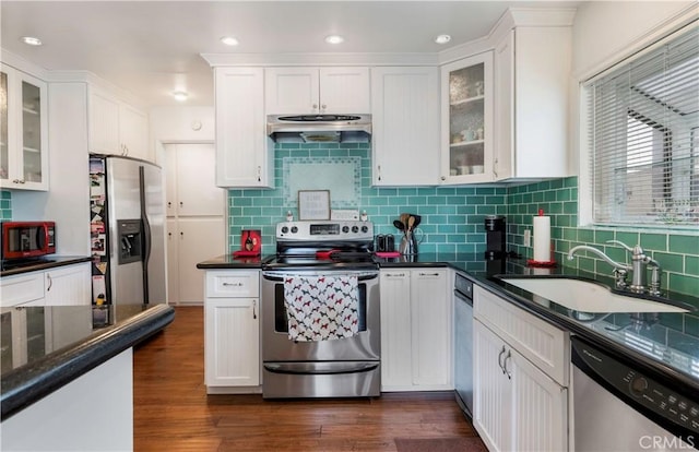 kitchen with sink, appliances with stainless steel finishes, dark hardwood / wood-style flooring, dark stone counters, and white cabinets