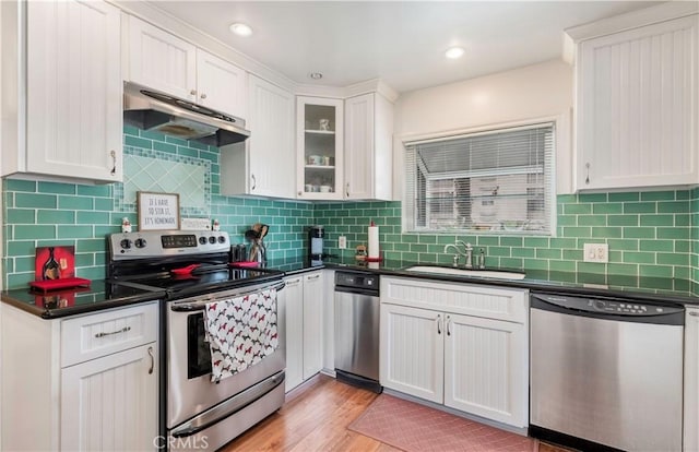 kitchen featuring sink, white cabinets, decorative backsplash, stainless steel appliances, and light wood-type flooring