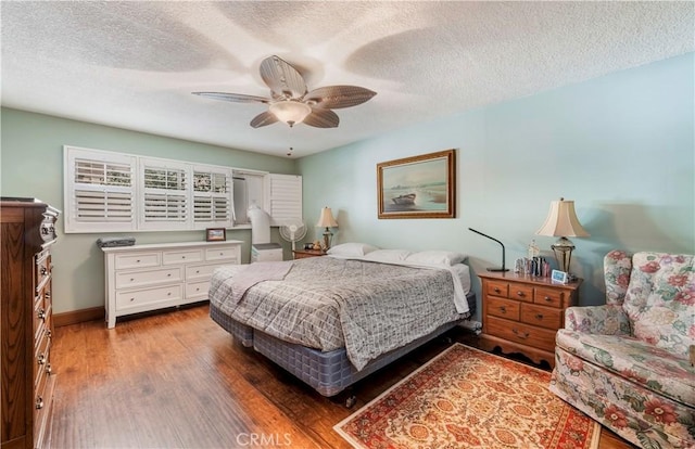 bedroom with ceiling fan, dark hardwood / wood-style floors, and a textured ceiling