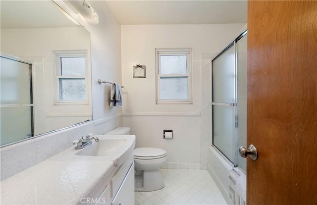 full bathroom featuring toilet, plenty of natural light, bath / shower combo with glass door, and vanity