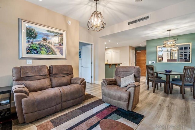 living room with light hardwood / wood-style floors and a notable chandelier