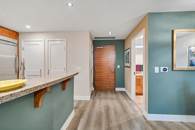 kitchen featuring a breakfast bar area, light hardwood / wood-style floors, and stainless steel refrigerator