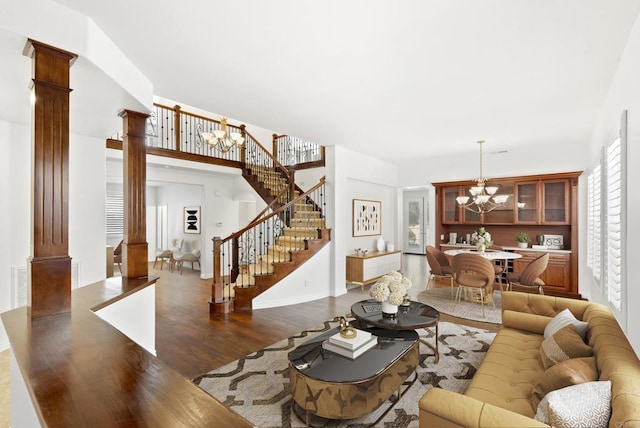 living room with decorative columns, an inviting chandelier, and dark hardwood / wood-style floors