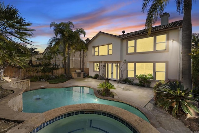 back house at dusk with a patio and a swimming pool with hot tub