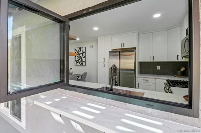 kitchen featuring sink, stainless steel appliances, white cabinetry, and backsplash