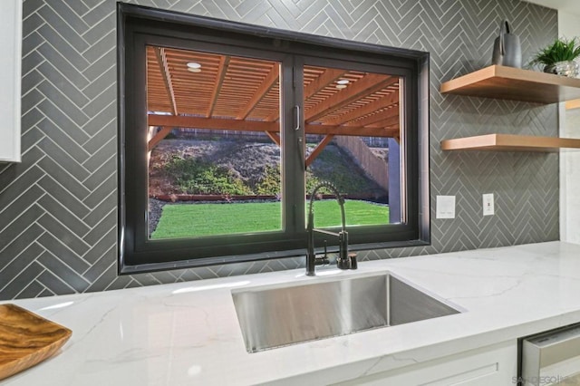 room details with light stone counters, white cabinets, and sink