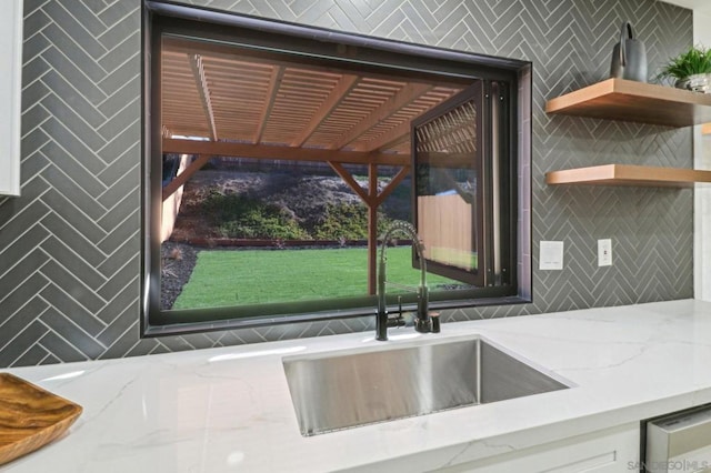 room details featuring sink, white cabinets, and light stone countertops