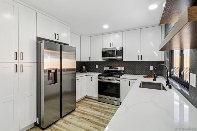 kitchen featuring sink, stainless steel appliances, light stone counters, and white cabinetry