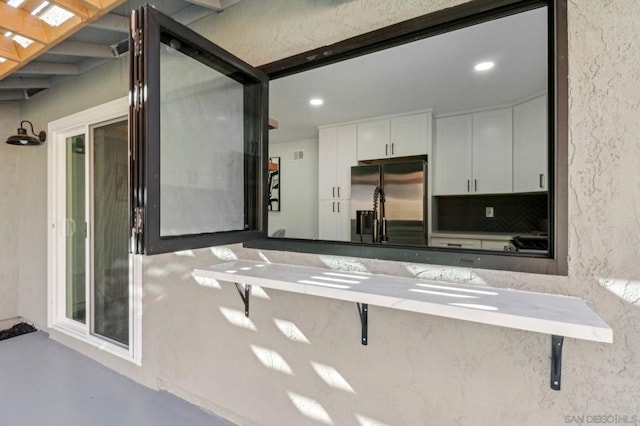 kitchen featuring white cabinets, stainless steel refrigerator with ice dispenser, and decorative backsplash