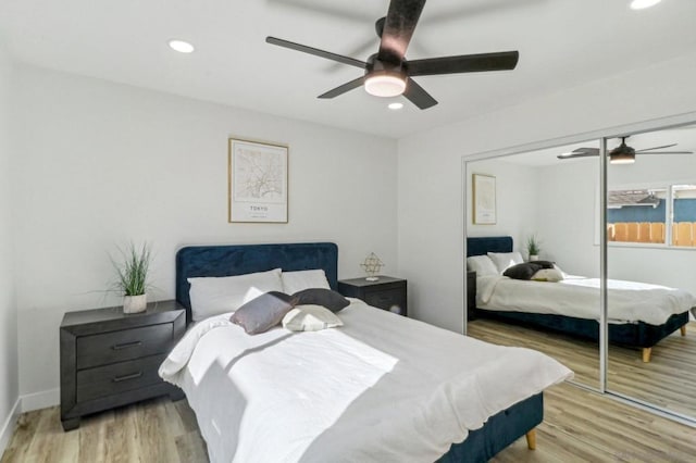 bedroom with ceiling fan, light hardwood / wood-style floors, and a closet