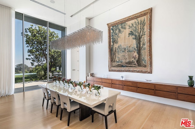 dining area with a towering ceiling and light wood-type flooring