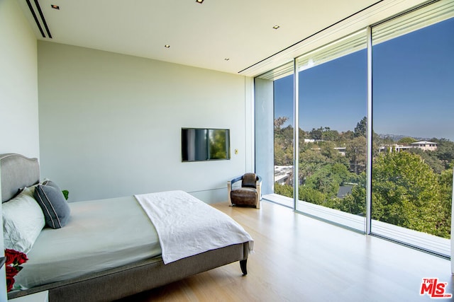 bedroom featuring access to exterior, light hardwood / wood-style floors, and expansive windows