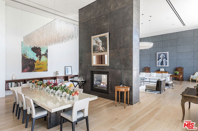 dining area with a high ceiling, light hardwood / wood-style flooring, and a fireplace