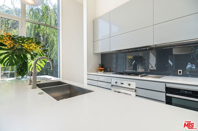 kitchen with sink, stainless steel appliances, white cabinetry, and backsplash