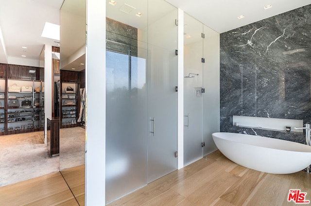 bathroom with tile walls, shower with separate bathtub, and hardwood / wood-style floors