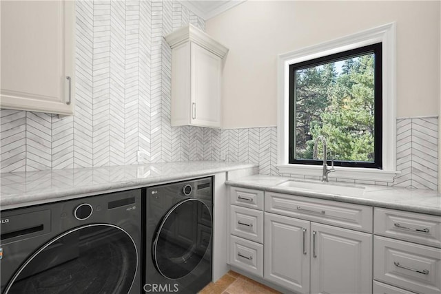 washroom featuring sink, washing machine and clothes dryer, a wealth of natural light, and cabinets