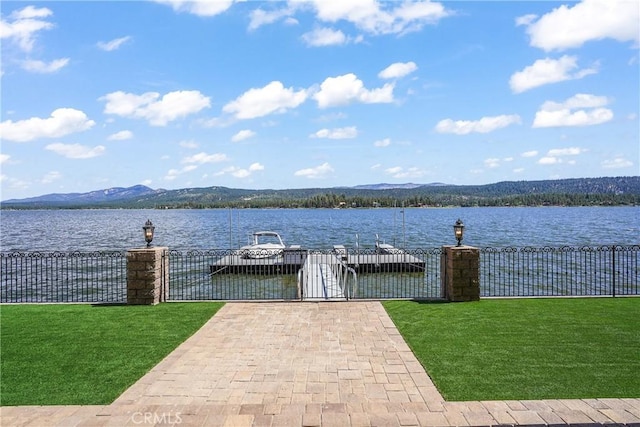 view of dock with a water and mountain view and a yard