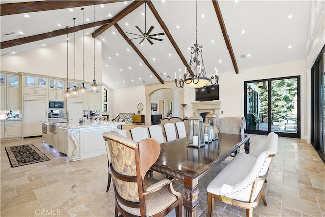 dining space with ceiling fan with notable chandelier, high vaulted ceiling, and beam ceiling