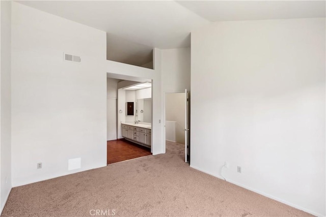 unfurnished bedroom featuring a sink, carpet flooring, visible vents, and connected bathroom