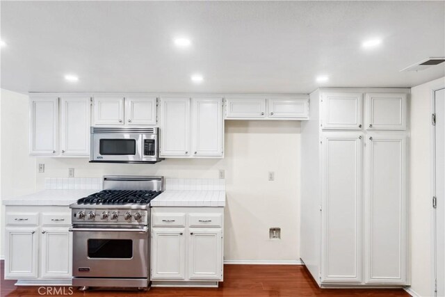 kitchen featuring appliances with stainless steel finishes, dark hardwood / wood-style floors, and white cabinetry