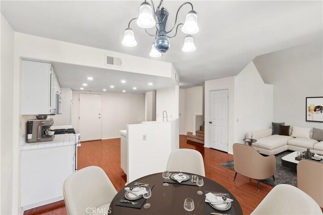 dining area featuring sink, a chandelier, and hardwood / wood-style flooring