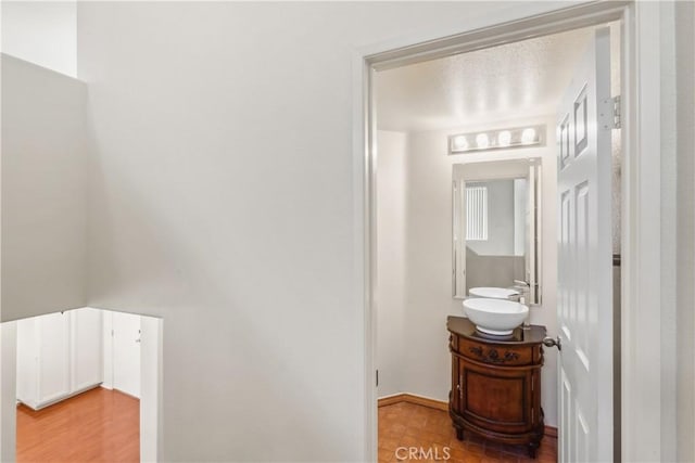 hallway featuring light wood-style flooring and a sink