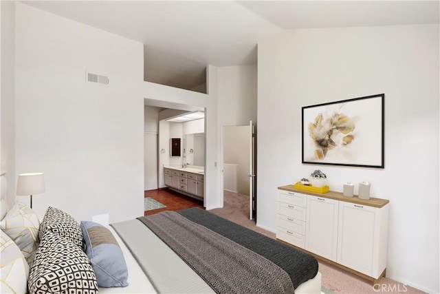 bedroom featuring connected bathroom, carpet floors, a sink, visible vents, and vaulted ceiling