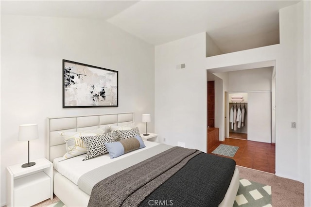 carpeted bedroom with a walk in closet, visible vents, and vaulted ceiling