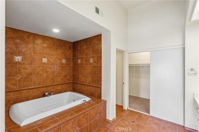 bathroom with tile patterned flooring and tiled tub