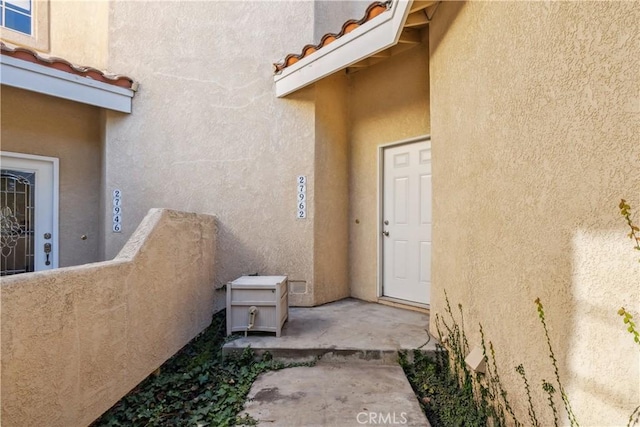 entrance to property featuring a tile roof and stucco siding