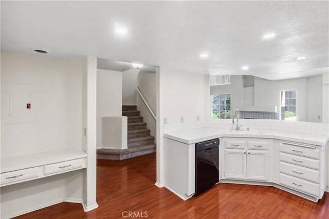 kitchen featuring kitchen peninsula, dark wood-type flooring, white cabinets, black dishwasher, and sink