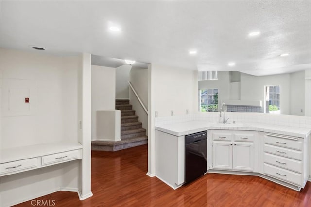 kitchen with a peninsula, wood finished floors, white cabinets, light countertops, and dishwasher