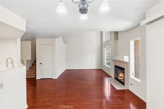 unfurnished living room with stairs, a fireplace, and wood finished floors