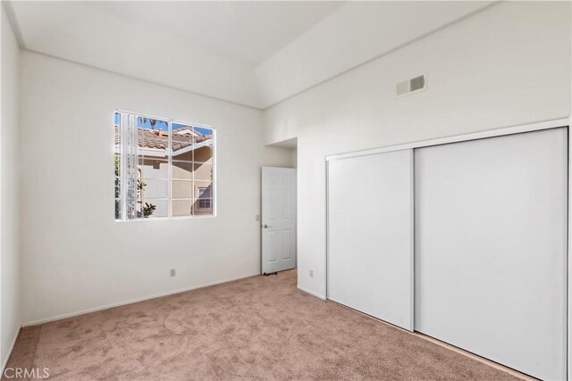 unfurnished bedroom with light colored carpet and a closet