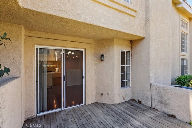 entrance to property featuring a wooden deck and stucco siding