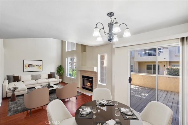 dining room featuring a tiled fireplace, wood finished floors, and an inviting chandelier