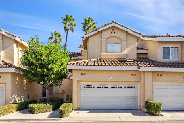 townhome / multi-family property featuring a garage, concrete driveway, a tiled roof, and stucco siding